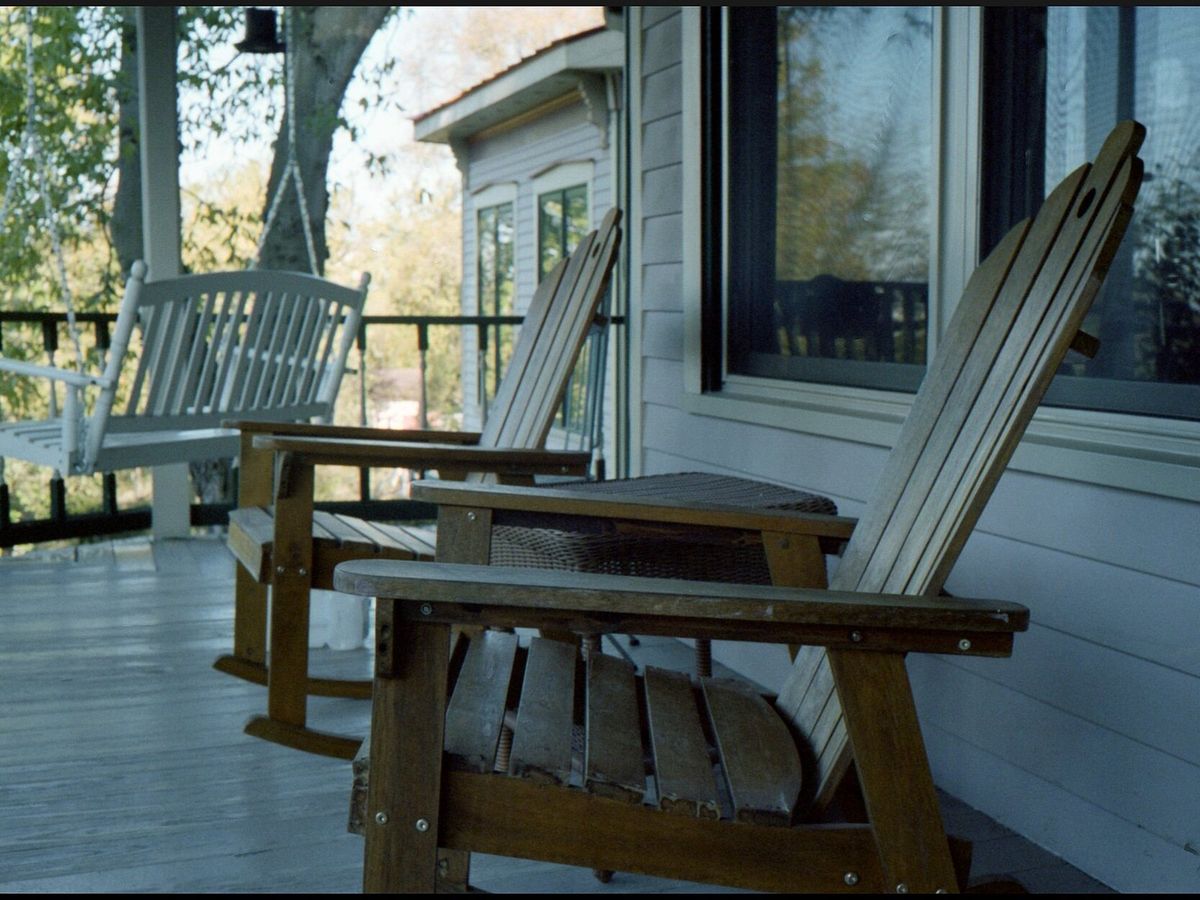 Wooden rocking chairs and a porch swing on a covered front porch