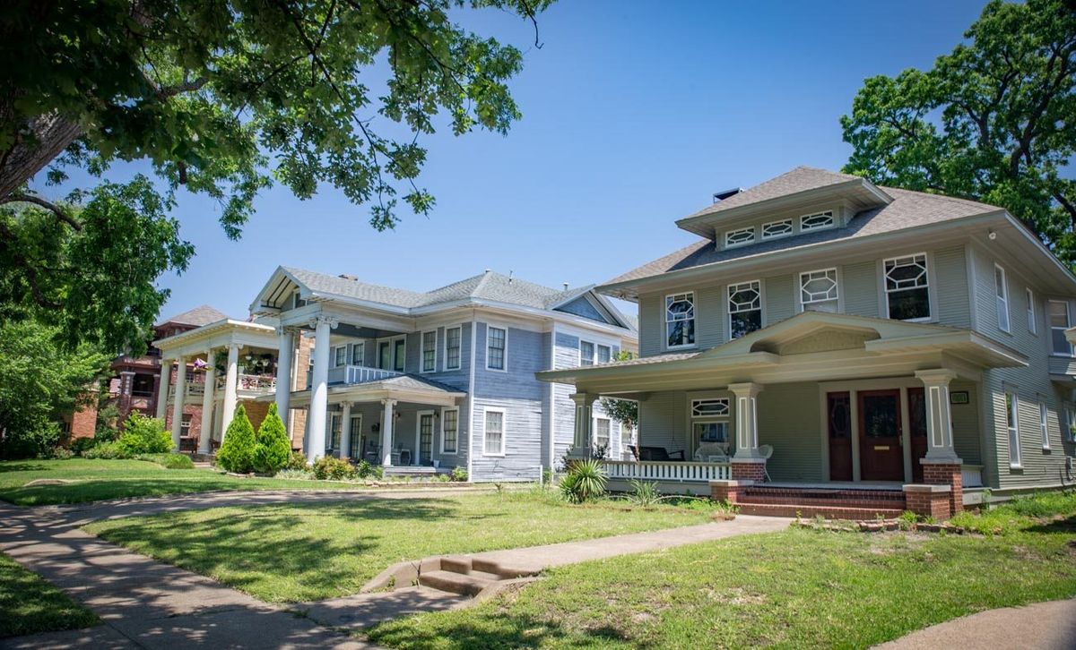 Two-story early 1900s houses with front porches along a street in the Munger Place Historic District